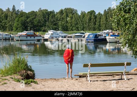 Ältere Frau am kleinen Sandstrand nach dem Schwimmen im Stadtteil Vähä-Meilahti in Helsinki, Finnland Stockfoto