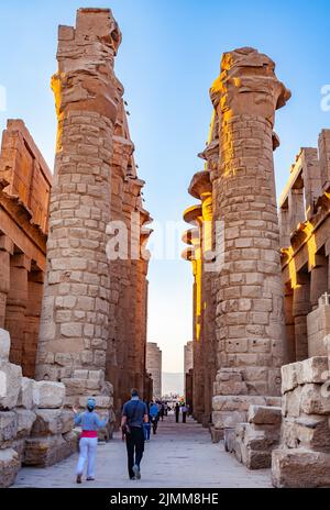 Touristen, die durch die große Hypostyle-Halle am Revier des Amun-Re im Karnak-Tempel spazieren. Stockfoto