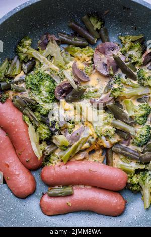 Gebratene Würstchen und Gemüse mit Pilzen und Hühnereier auf einer Pfanne Stockfoto