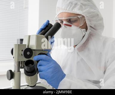 Arzt mit Mikroskop überprüfen kovid Probe Stockfoto