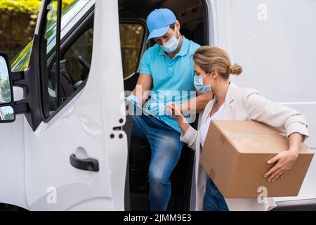 Frau, die das Paket vom Lieferer in einem Lieferwagen erhält Stockfoto