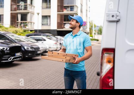 Ein Kurier, der Pizza geliefert hat, wartet auf einen Kunden Stockfoto