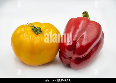 Ganze gelbe Tomaten und rote Paprika Nahaufnahme gegen Weiß Stockfoto