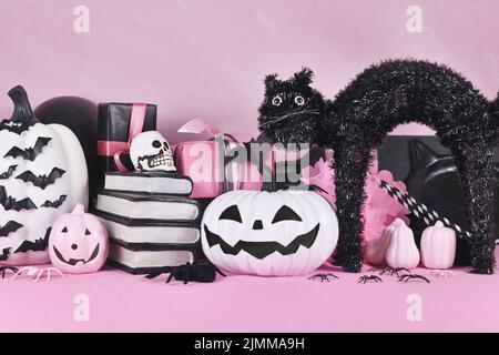 Pinkes Halloween Dekor mit schwarzen und weißen Kürbissen, Spell Booksm Katze und Spinnen Stockfoto