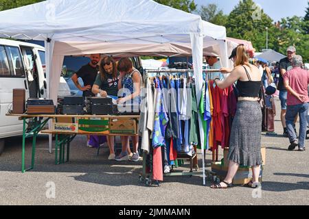 Heidelberg, Deutschland - August 2022: Frau schaut mit alten Second-Hand-Klamotten durch das Regal auf dem Flohmarkt Stockfoto