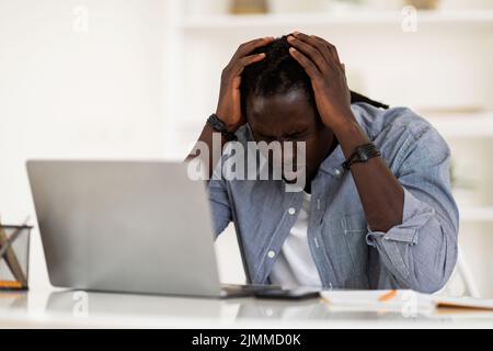 Deprimierter Schwarzer Mann, Der Kopfschmerzen Bei Der Arbeit Mit Dem Laptop Im Home Office Hat Stockfoto