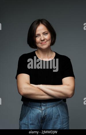 Positive Frau mittleren Alters trägt schwarzes T-Shirt mit leerem Platz Stockfoto