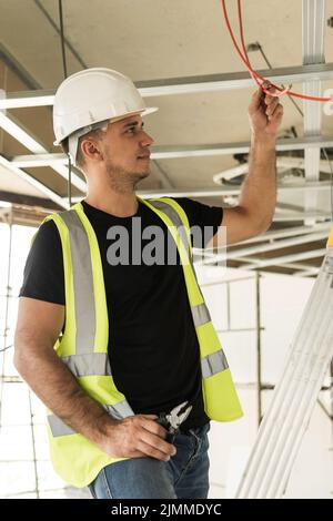 Elektriker schneidet Drähte während seiner Arbeiten auf einer Baustelle Stockfoto