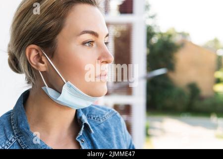 Frau mit Präventionsmaske geht nach draußen, um tief durchzuatmen Stockfoto