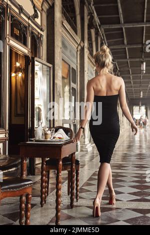 Wunderschöne Frau trägt schwarzes Kleid in einem Vintage-Café Stockfoto