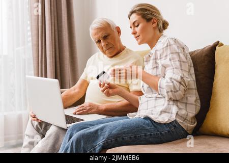 Frau, die älteren Männern erklärt, wie sie E-Payment-Dienste nutzen Stockfoto
