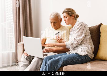 Frau, die älteren Männern erklärt, wie sie E-Payment-Dienste nutzen Stockfoto