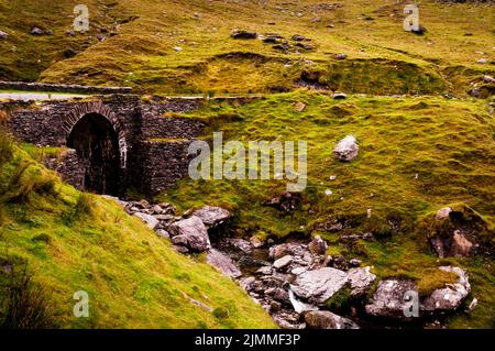 Eine bogenförmige Steinbrücke an der Straße zur Gap of Dunloe, Ring of Beara im County Kerry, Irland. Stockfoto