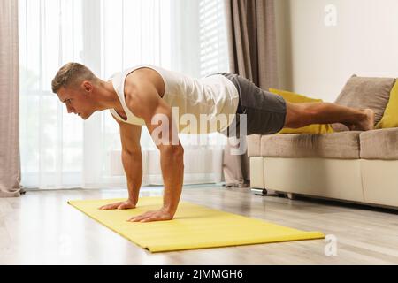 Muskulöser Mann, der Liegestütze während des Heimtrainings macht Stockfoto