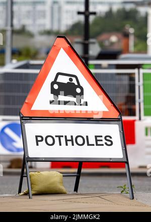 Warnschild für die Gefahr von Schlaglöchern gefährliche Straßenbedingungen. Rote Dreieck Pot Hole Meldung Warnung Fahrer Mangel an Autobahn Reparaturen und Wartung. Stockfoto