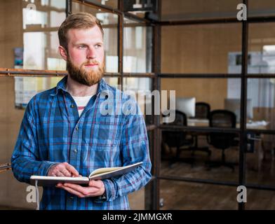 Betrachten des jungen kaukasischen Mannes, der Milchdenken hält Stockfoto