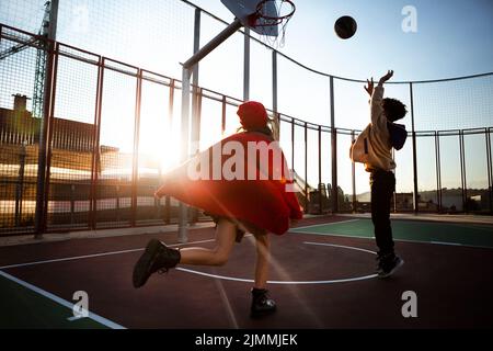 Kinder spielen gemeinsam im Freien Basketball Stockfoto