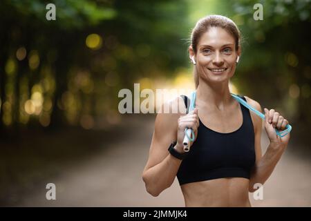 Fröhliche Frau beim Training im Freien, mit Springseil Stockfoto
