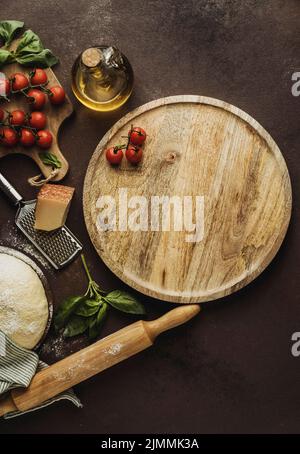 Pizzateig flach mit Holzbretttomaten legen Stockfoto