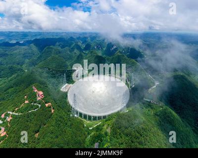 (220806) -- GUIZHOU, 6. August 2022 (Xinhua) -- Luftfoto vom 21. Juli 2022 zeigt Chinas fünfhundert Meter langes Aperture Spherical Radio Telescope (FAST), das in der südwestlichen Provinz Guizhou in Betrieb ist. Das Hotel befindet sich in einer natürlich tiefen und runden Karstniederlage in der südwestlichen chinesischen Provinz Guizhou und begann IM Januar 2020 MIT der offiziellen Operation und wurde am 31. März 2021 offiziell der Welt eröffnet. Es wird angenommen, dass es das empfindlichste Radioteleskop der Welt ist. Mit FAST haben Wissenschaftler über 660 neue Pulsare identifiziert. (Xinhua/Ou Dongqu) Stockfoto