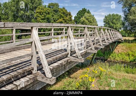 Münster, 28. Juli 2022: Verwitterte Holzbrücke über die Ems in grüner Landschaft an einem sonnigen Sommertag Stockfoto