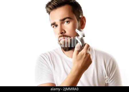 Ein hübscher bärtiger Mann verwendet einen elektrischen Trimmer Stockfoto