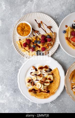 Blick von oben auf den Teller mit Frühstückscrepes mit Beeren und Bananen Stockfoto