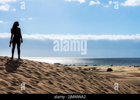 Die Frau blickt bei Sonnenuntergang auf Gran Canaria über die Dünen zum Meer Stockfoto