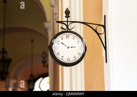 Altmodische Analoguhr, die im Freien an der Gebäudewand hängt Stockfoto