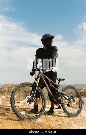 Downhillfahrer voll ausgestattet mit Schutzausrüstung und seinem Fahrrad Stockfoto