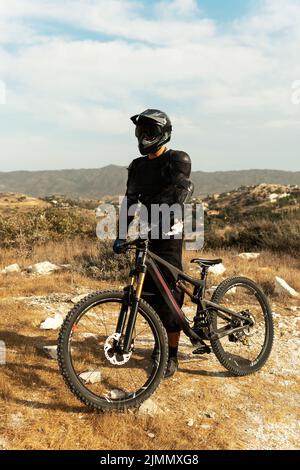 Downhillfahrer voll ausgestattet mit Schutzausrüstung und seinem Fahrrad Stockfoto