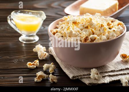 Popcornschüssel und geschmolzene Butter auf dem Küchentisch Stockfoto