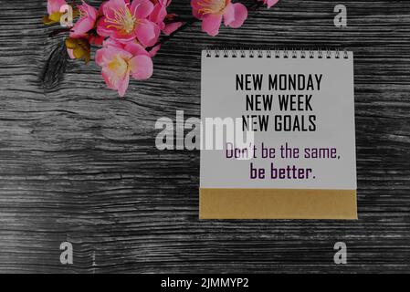 Positive geschäftliche Motivationsbotschaft auf Kalendercover – Neuer Montag. Neue Woche. Neue Ziele. Seien Sie nicht gleich. Sei besser. Mit rosa Blume auf dem Tisch. Stockfoto