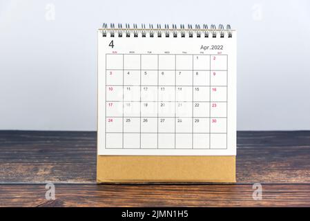 Der Tischkalender für April 2022 mit weiß blauem Hintergrund auf dem Holztisch. Hallo April englischer Kalender. Willkommen Monat April 2022 Konzept. Stockfoto