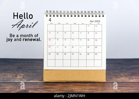 April 2022 Kalender auf Holz rustikalen Tisch mit positiver Textnachricht- Hallo April. Sei ein Monat voller Freude und Erneuerung. Willkommen im April 2022. Stockfoto