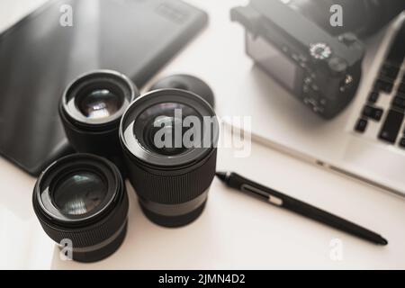 Arbeitsplatz mit moderner Ausrüstung für die Fotografie. Spiegellose Kamera und Objektive mit Festbrennweite. Stockfoto