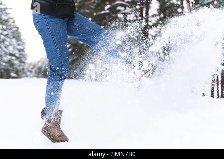 Frau trägt Schaffellstiefel und tritt Schnee Stockfoto