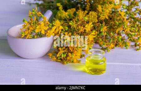 Johanniskraut-Blumenöl in einer Glasflasche. Auf einem hölzernen Hintergrund. Selektiver Fokus Stockfoto