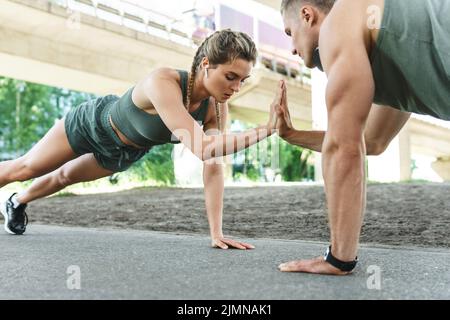 Sportliches Paar und Fitnesstraining im Freien. Mann und Frau tun Liegestütze Übung. Stockfoto