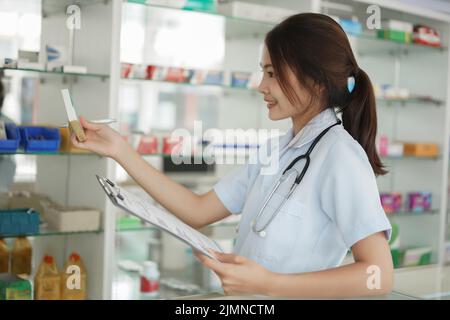Medizin- und Gesundheitskonzept, Apothekerin hält Medikamentenbox und Rezept in der Apotheke. Stockfoto