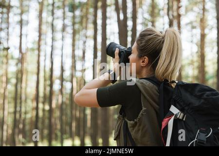 Wanderer, der mit einer modernen spiegellosen Kamera im grünen Wald fotografiert Stockfoto