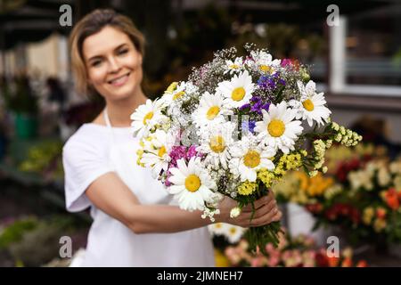 Frau Floristin mit einem Blumenstrauß in ihrem kleinen Blumenladen Stockfoto