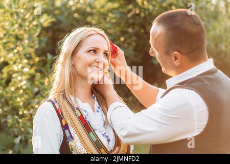 Ehemann und Ehefrau in serbischer traditioneller Kleidung. Ehemann setzte stieg hinter seine Frau Ohr Stockfoto