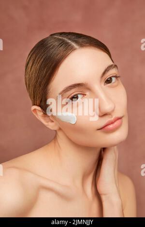 Smiley Frau posiert mit Gesichtscreme aus der Nähe Stockfoto