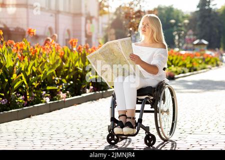 Frau Rollstuhl suchen Karte im Freien Stockfoto