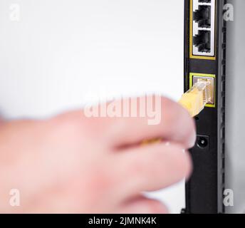 Stecken Sie das ethernet-Kabel von Hand in den Router ein Stockfoto