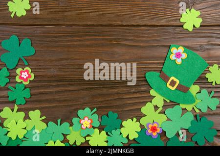 Happy Saint Patrick's Mockup aus handgefertigten Filzhut-Blumen und Kleeblättern auf Holzhintergrund. Stockfoto