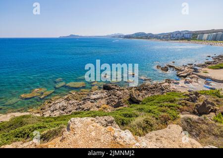 Wunderschöne Aussicht auf die Menschen am Privatstrand mit Sonnenliegen und Sonnenschirmen an der felsigen Küste. Griechenland. Stockfoto