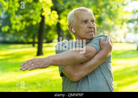 Älterer Mann, der während seines Fitnesstrainings im grünen Stadtpark trainiert Stockfoto