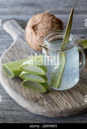 Kokoswasser mit Aloe Vera Stücken auf einem rustikalen Brett, bereit zum Trinken. Stockfoto